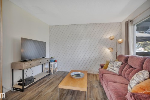 Living area featuring wood-finish flooring, a bright window, and an accent wall with diagonal paneling - 305 3 St, Rural Wetaskiwin County, AB - Indoor Photo Showing Living Room