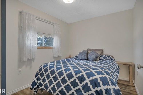 Well-lit room featuring neutral wall paint, wood-finish flooring, a single window with a wood-finish sill, and a ceiling-mounted light fixture - 305 3 St, Rural Wetaskiwin County, AB - Indoor Photo Showing Bedroom