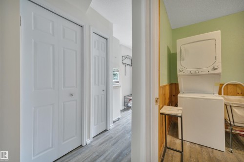 Utility area featuring a stacked washer and dryer, light green walls, and wood paneling - 305 3 St, Rural Wetaskiwin County, AB - Indoor Photo Showing Laundry Room
