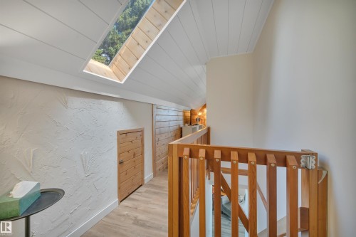 Upper-level walkway featuring a wood-finish floor and a sloped white shiplap ceiling with an integrated skylight - 305 3 St, Rural Wetaskiwin County, AB - Indoor Photo Showing Other Room