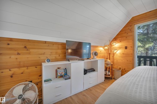 Wood-finish flooring with natural wood plank walls and a white sloped ceiling - 305 3 St, Rural Wetaskiwin County, AB - Indoor Photo Showing Bedroom