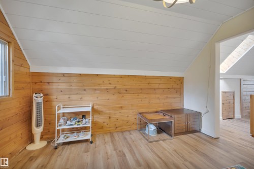 Room featuring wood-finish flooring, wood plank wall paneling, and a sloped white paneled ceiling - 305 3 St, Rural Wetaskiwin County, AB - Indoor Photo Showing Other Room With Fireplace