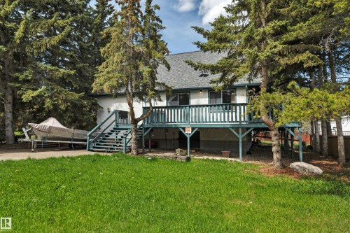 Rear exterior featuring a spacious elevated deck with a durable railing, dual exterior staircases, and a gravel pad - 305 3 St, Rural Wetaskiwin County, AB - Outdoor With Deck Patio Veranda