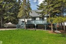 Rear exterior featuring a spacious elevated deck with a durable railing, dual exterior staircases, and a gravel pad - 305 3 St, Rural Wetaskiwin County, AB  - Outdoor With Deck Patio Veranda 