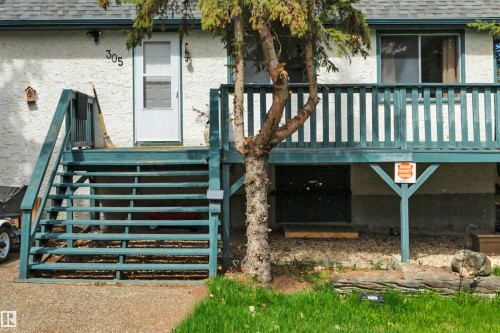 Outdoor deck with stairs, featuring a white door and sliding window - 305 3 St, Rural Wetaskiwin County, AB - Outdoor