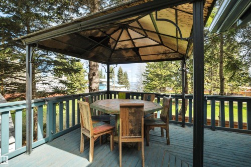 Spacious outdoor deck featuring a metal-framed gazebo with a translucent roof, painted wood railings, and a wood-finish floor - 305 3 St, Rural Wetaskiwin County, AB - Outdoor With Deck Patio Veranda With Exterior