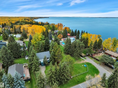 Aerial perspective showcasing a residential area bordered by a large body of water and dense forest - 305 3 St, Rural Wetaskiwin County, AB - Outdoor With Body Of Water With View