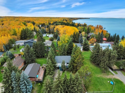Expansive waterfront property featuring a treed shoreline, a large body of water, and a residential area with varied housing styles - 305 3 St, Rural Wetaskiwin County, AB - Outdoor With Body Of Water With View