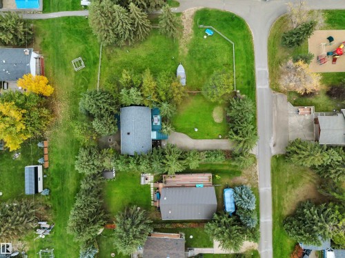 Property featuring a main residence with an attached garage, surrounded by mature trees and a manicured lawn - 305 3 St, Rural Wetaskiwin County, AB - Outdoor With View