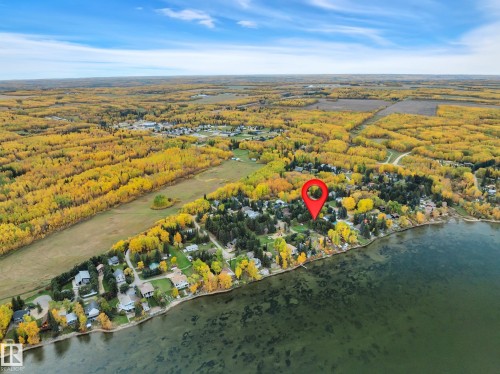 Aerial perspective featuring a lakeside property within a wooded community - 305 3 St, Rural Wetaskiwin County, AB - Outdoor With View