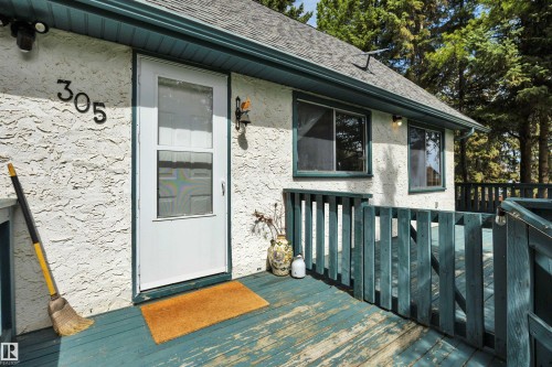 Stucco exterior with number signage and a white storm door - 305 3 St, Rural Wetaskiwin County, AB - Outdoor With Deck Patio Veranda With Exterior