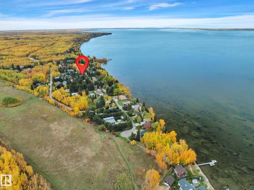 Lakeside community featuring mature trees, diverse residential structures, and a clear blue lake - 305 3 St, Rural Wetaskiwin County, AB - Outdoor With Body Of Water With View