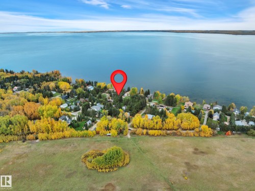 Waterfront community setting with residential properties nestled among mature trees - 305 3 St, Rural Wetaskiwin County, AB - Outdoor With Body Of Water With View