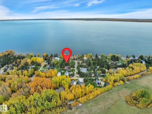 Waterfront community featuring mature trees, residential properties, and a natural shoreline - 305 3 St, Rural Wetaskiwin County, AB - Outdoor With Body Of Water With View