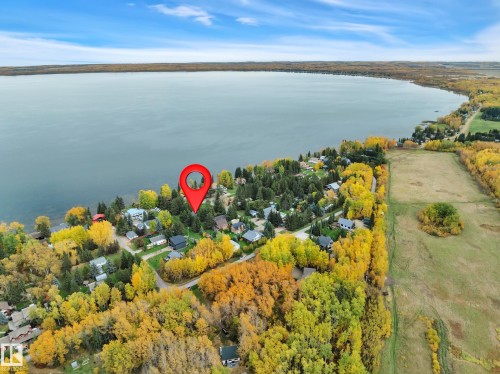 Waterfront property featuring a prominent red location marker, surrounded by dense trees, and a residential area - 305 3 St, Rural Wetaskiwin County, AB - Outdoor With Body Of Water With View