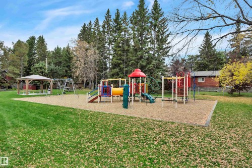 Expansive recreational area featuring a colorful playground structure with slides and climbing elements, a swing set, and a covered gazebo - 305 3 St, Rural Wetaskiwin County, AB - Outdoor With Backyard
