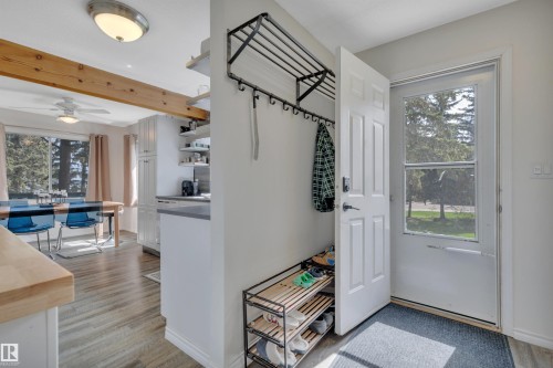 Entryway mudroom area featuring a white door with a window, wood-finish flooring, a ceiling-mounted light fixture, and an open concept layout into the dining area - 305 3 St, Rural Wetaskiwin County, AB - Indoor Photo Showing Other Room