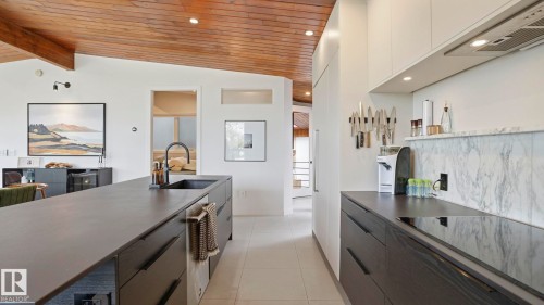 Modern kitchen featuring a large central island with an integrated sink and black faucet - 6412 Ada Boulevard, Edmonton, AB - Indoor Photo Showing Kitchen