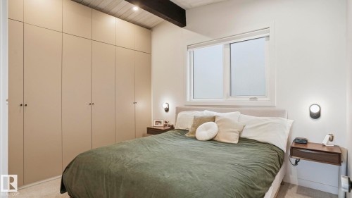 Integrated custom cabinetry spanning a full wall, complemented by a textured ceiling and exposed structural beam - 6412 Ada Boulevard, Edmonton, AB - Indoor Photo Showing Bedroom