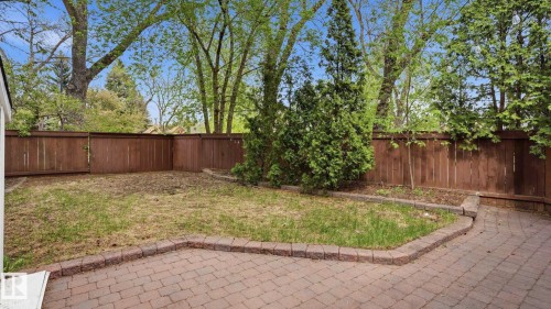 Expansive backyard featuring a paver patio, partial lawn area, wood privacy fencing, and mature trees - 6412 Ada Boulevard, Edmonton, AB - Outdoor