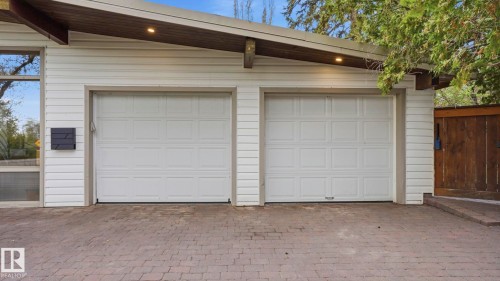 Two-car garage featuring paneled white doors, white horizontal siding, and a paver driveway - 6412 Ada Boulevard, Edmonton, AB - Outdoor With Exterior
