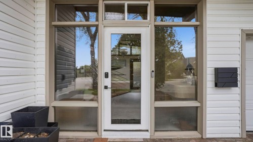 Modern entry featuring a full-light door with sidelights, transom windows, textured glass accents, and white horizontal siding - 6412 Ada Boulevard, Edmonton, AB - Outdoor With Exterior