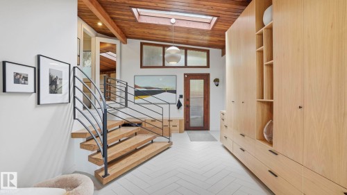 Entry foyer featuring custom built-in cabinetry, wood-finish flooring in a herringbone pattern, and a natural wood-plank ceiling with exposed beams - 6412 Ada Boulevard, Edmonton, AB - Indoor Photo Showing Other Room