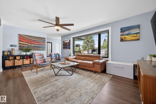 Open-concept living space featuring wood-finish flooring, a large picture window, and a ceiling fan with integrated lighting - 6707 92B Avenue, Edmonton, AB - Indoor Photo Showing Living Room