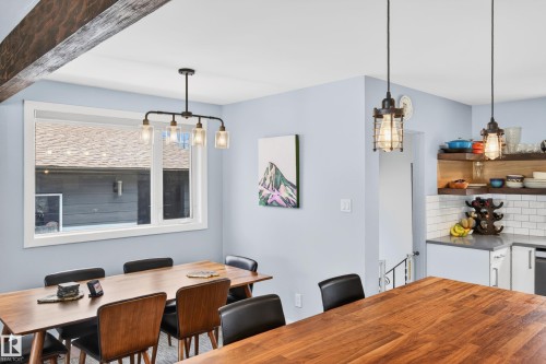 Open-concept dining area featuring a wood-finish dining table and an industrial-style chandelier - 6707 92B Avenue, Edmonton, AB - Indoor Photo Showing Dining Room