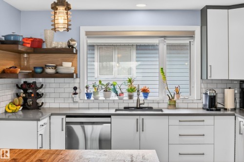 Contemporary kitchen featuring a stainless steel dishwasher, a single-basin sink with a gooseneck faucet, light grey countertops, and white subway tile backsplash - 6707 92B Avenue, Edmonton, AB - Indoor Photo Showing Kitchen With Upgraded Kitchen