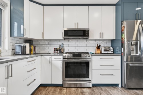 Modern kitchen featuring white shaker-style cabinetry, a stainless steel gas range, and a built-in microwave - 6707 92B Avenue, Edmonton, AB - Indoor Photo Showing Kitchen With Upgraded Kitchen