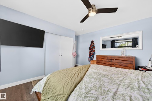 Bedroom featuring wood-finish flooring, a ceiling fan with integrated lighting, a wall-mounted flat panel display, and sliding closet doors - 6707 92B Avenue, Edmonton, AB - Indoor Photo Showing Bedroom
