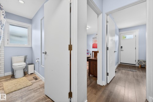 Bathroom featuring a white toilet, subway tile shower surround, and wood-finish flooring - 6707 92B Avenue, Edmonton, AB - Indoor