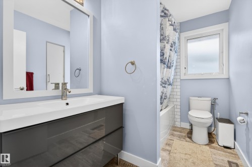 Modern bathroom featuring a single vanity with integrated sink, rectangular framed mirror, and a white subway-tiled bath with shower - 6707 92B Avenue, Edmonton, AB - Indoor Photo Showing Bathroom