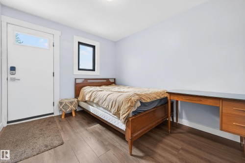 Room featuring wood-finish flooring, a white door with transom window, and a window with black trim - 6707 92B Avenue, Edmonton, AB - Indoor Photo Showing Bedroom