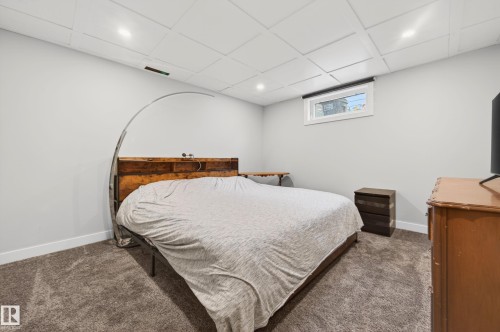 Bedroom featuring light gray walls, gray carpet flooring, a white coffered ceiling with recessed lighting, and a window with a white frame - 6707 92B Avenue, Edmonton, AB - Indoor Photo Showing Bedroom