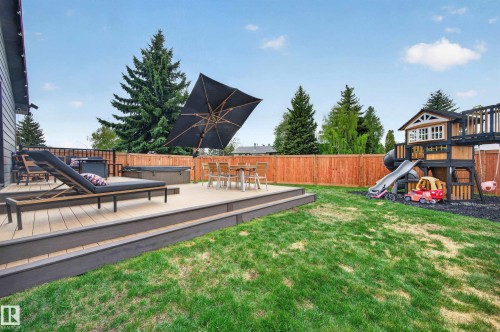 Expansive backyard featuring a multi-level composite deck, a built-in spa, a privacy fence, and mature evergreen trees - 6707 92B Avenue, Edmonton, AB - Outdoor With Deck Patio Veranda