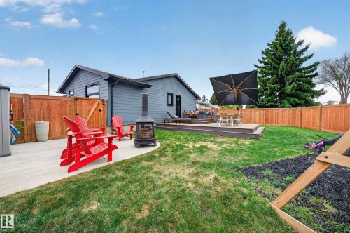 Expansive backyard featuring a multi-level composite deck, mature evergreen tree, concrete patio, and a wood privacy fence - 6707 92B Avenue, Edmonton, AB - Outdoor With Deck Patio Veranda