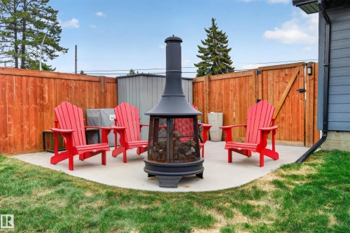 Concrete patio featuring a freestanding outdoor fireplace, a wood fence, and a gate - 6707 92B Avenue, Edmonton, AB - Outdoor