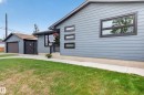 Contemporary exterior featuring light blue siding, black-framed windows, and a detached garage with a brown door - 6707 92B Avenue, Edmonton, AB  - Outdoor 