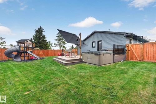 Expansive backyard featuring a manicured lawn, multi-level composite deck, built-in hot tub, and a privacy fence - 6707 92B Avenue, Edmonton, AB - Outdoor With Deck Patio Veranda