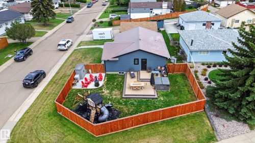 Backyard featuring a wooden privacy fence, a multi-level deck with a built-in fire table, and a dedicated play structure area - 6707 92B Avenue, Edmonton, AB - Outdoor