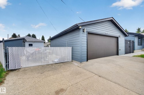 Detached two-car garage with a dark brown overhead door, concrete driveway, and light blue siding - 6707 92B Avenue, Edmonton, AB - Outdoor With Exterior