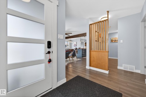 Entryway featuring a modern door with frosted glass panels, wood-finish flooring, and a decorative slatted wood partition - 6707 92B Avenue, Edmonton, AB - Indoor Photo Showing Other Room