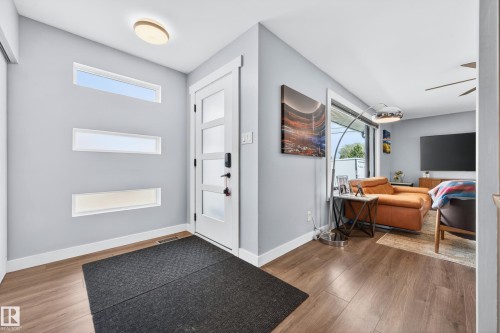 Entryway featuring a contemporary white door with frosted glass panels, horizontal window accents, and wood-finish flooring - 6707 92B Avenue, Edmonton, AB - Indoor Photo Showing Other Room