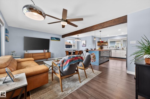 Open-concept living space featuring wood-finish flooring, exposed ceiling beams, and a modern ceiling fan - 6707 92B Avenue, Edmonton, AB - Indoor