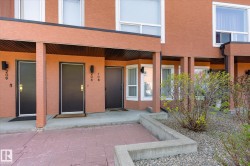 Multi-unit building exterior featuring a textured orange facade and white-framed windows - 