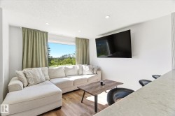 Bright interior space featuring a large picture window, recessed ceiling lighting, and wood-finish flooring - 