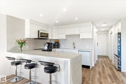 Modern kitchen featuring white flat-panel cabinetry, a light-toned countertop, and a built-in microwave - 