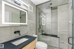 Contemporary bathroom featuring a floating vanity with a dark speckled countertop, an integrated rectangular sink, and a matte black wall-mounted faucet - 